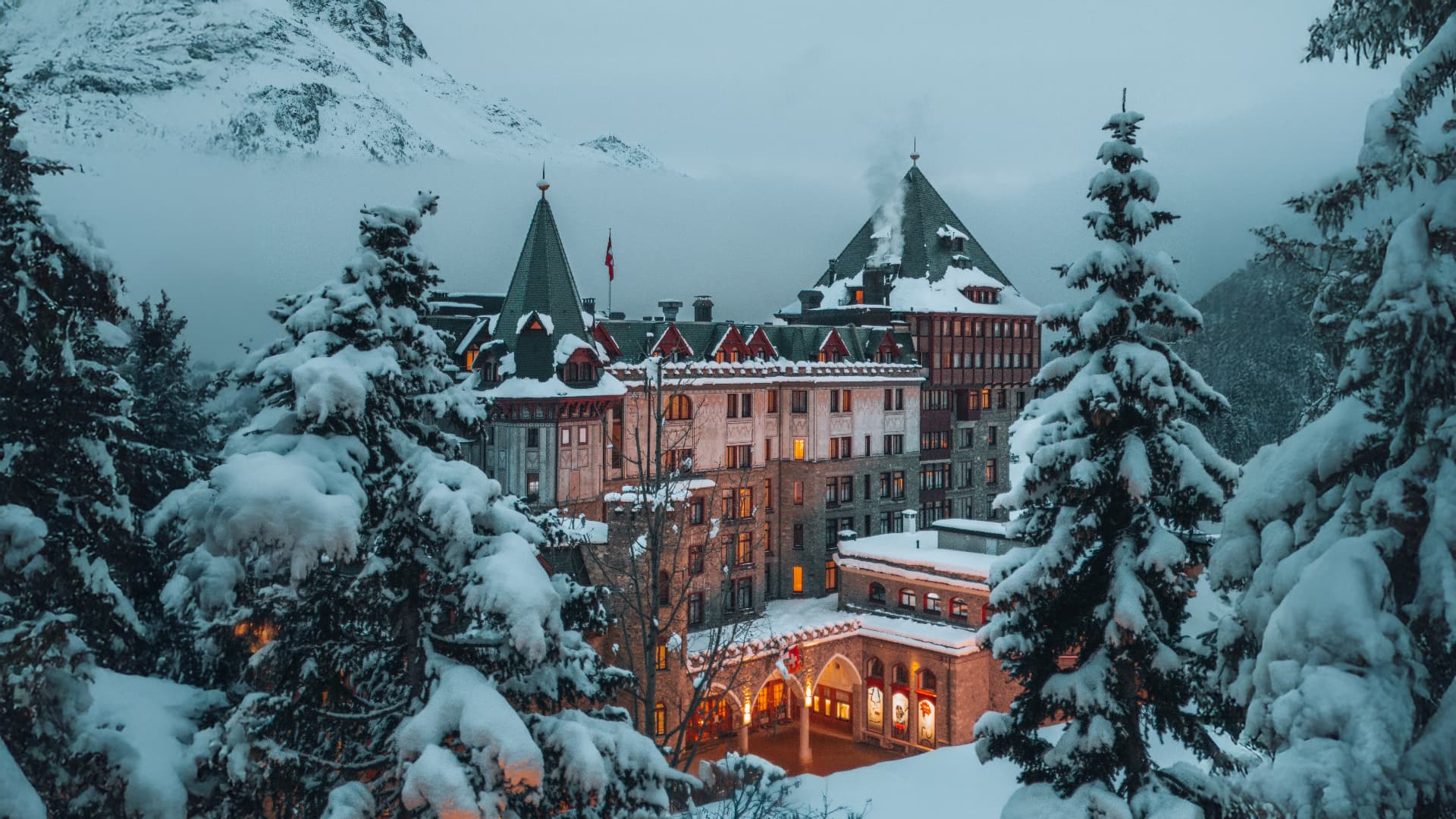 Badrutt's Palace hotel exterior in winter, seen through snow-covered trees
